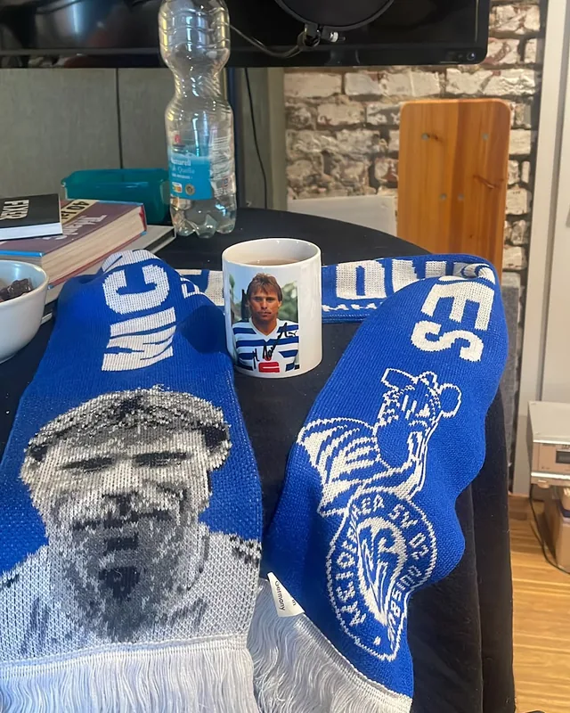 Fanschal und eine Tasse mit dem Porträt von Michael Tönnies vor dem Studiomikrofon