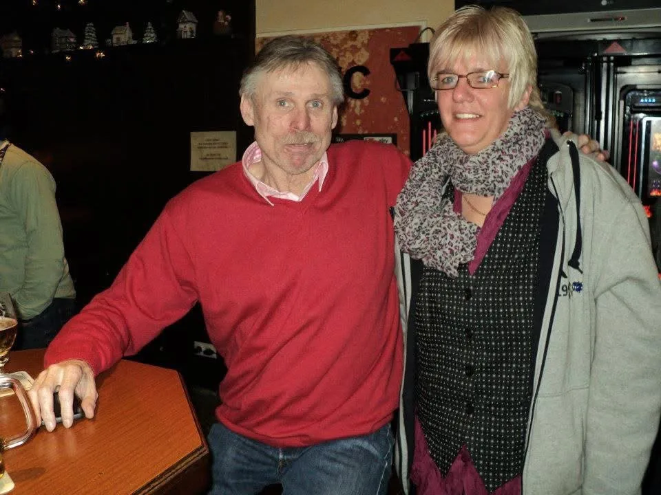 Michael Tönnies im roten Pullover legt den Arm um Nicki Beaujean in einer weihnachtlich geschmückten Kneipe