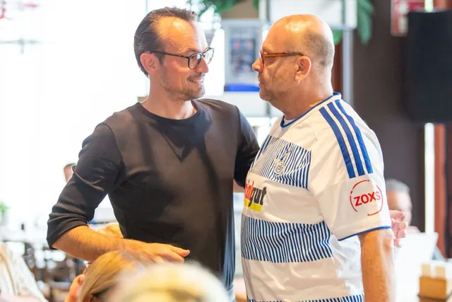 Ein Mann im schwarzen Pullover und ein Mann im MSV-Trikot begrüßen sich herzlich